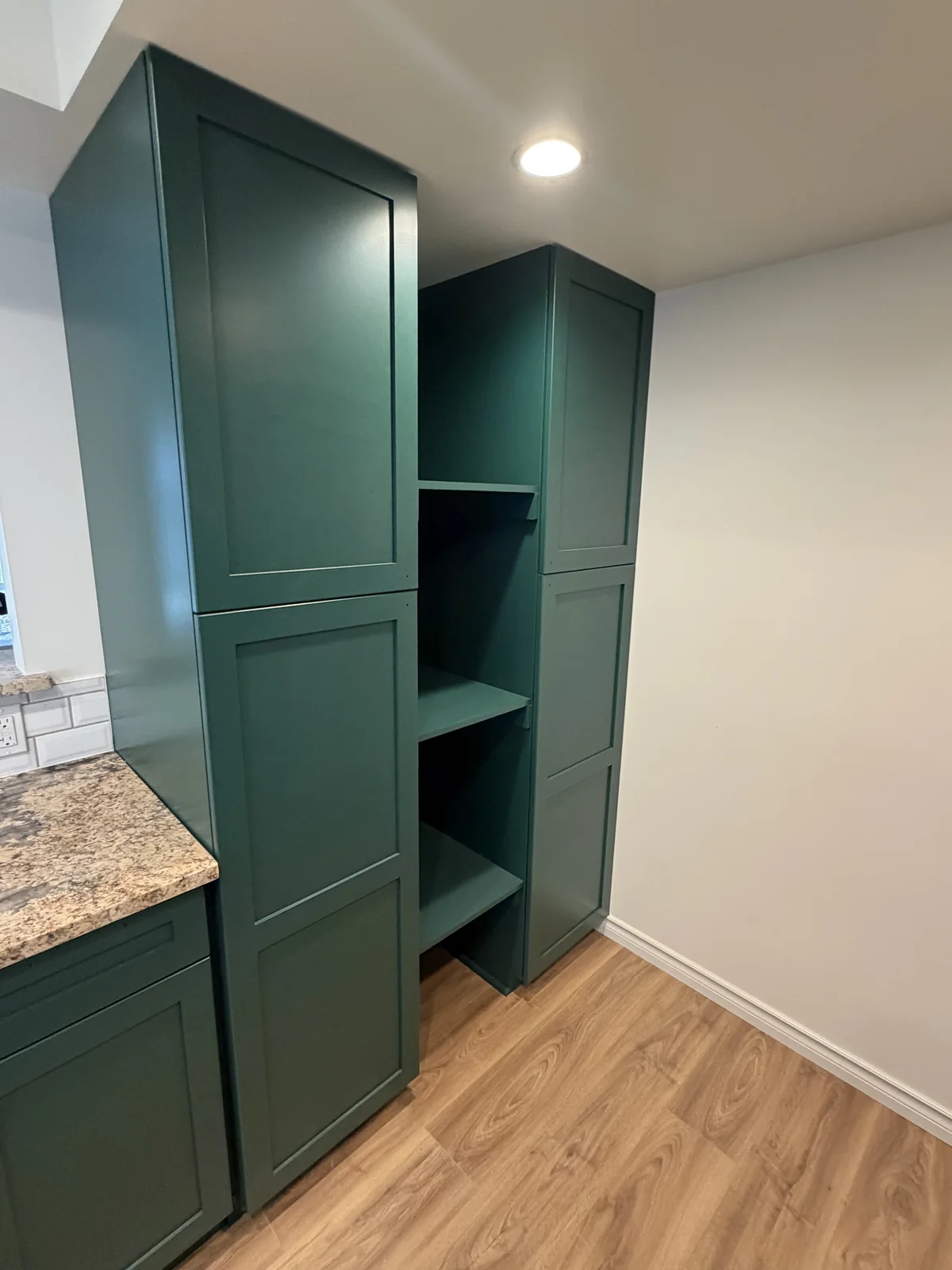 Dark green painted tall kitchen cabinetry and open shelving